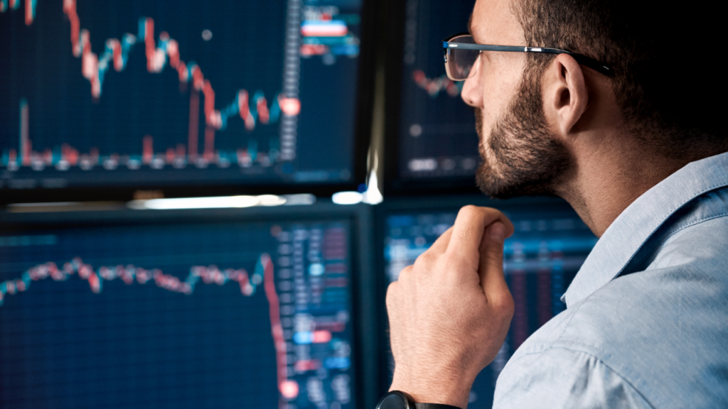 – PU Prime | More Than Trading man looking at multiple screen monitors with cfd trading charts